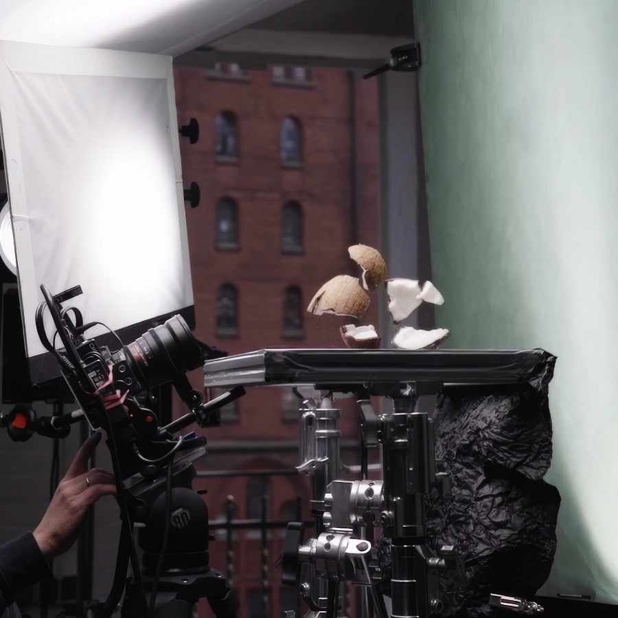 A studio situation with a camera filming a shattering coconut in front of a green screen.